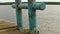 Close up view of old rusty bollard with defocused water and forest at background. End of summmer time and loneliness