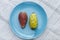 Close up view of pair of red a yellow indian figs also called prickly pear on a blue plate