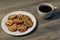 Close up view photo of tasty homemade crunchy with chocolate drops cookies on white round crockery kitchen plate and cup of hot mo