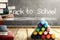 Close up view of pile of books and colorful crayons on wooden table and blackboard with Back to School message