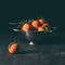 close up view of pile of mandarins with leaves in strainer on dark