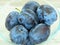 Close up View of Plums in Glass Bowl and Grey-White Background.