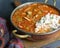 Close up view of a pot of gumbo and scoop of white rice, made with okra, sausage and chicken.