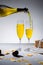 close up view of pouring yellow champagne into glasses process and wrapped gift