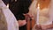 Close-up view of priest hands putting wedding rings on the hand of a bride. Newlyweds during wedding ceremony in