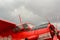 Close up view of red airplane biplane with piston engine and propeller on the cloudy sky background
