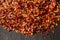 Close up view of red chili flakes on black slate background with selective focus. Crushed red cayenne pepper. Top view.