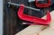 Close up view of red clamp tool for wood crafting work that is put on wood table with pencil and the other equipment