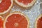 Close up view of the red grapefruit slices in lemonade background. Texture of cooling sweet summer drink with macro