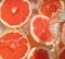 Close up view of the red grapefruit slices in lemonade background. Texture of cooling sweet summer drink with macro