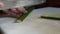 Close up view of removing inedible parts and cutting cucumber into thin slices. Green vegetables preparation on a