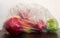 Close-up view of a ripe red and green apples, a source of vitamins, packed in a transparent plastic bag, environmental pollutant,