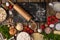 Close-up view of rolling pin with black chopped board on wooden table with variety of ingredients background. Concept of cooking