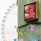 Close up view of a rusty metal column with stickers and a red phone booth photo on it with the London Eye on the background.
