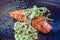 Close up view on Salmon steak in dark facture plate served with green sauce. Selective focus on Fish meal. Cooked salmon steak for