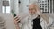 Close up view of senior grey haired man waving and blowing kiss while finishing video call. Positive bearded pensioner