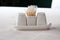 Close-up view of a set of cups for spices, salt, peppers and toothpicks, standing on a white table.