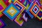 Close-up view of a set of hand-knitted yarn mobiles in a variety of colorful squares hanging