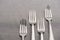 Close up view of shiny forks on grey tablecloth