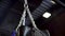 Close-up view of silver chain and swaying black punching bag, action, sport concept. Swinging chain with hanging boxing