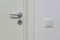 Close up view of silver door handle and  white light switch isolated. Building construction elements concept