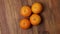 Close up view of slowly rotating four ripe orange mandarins fruit isolation on wood background