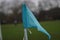 Close-up view of a small blue flag atop a pole against a lush green field