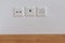 Close up view of sockets for television, internet, telephone and electricity on a white wall and wood floor