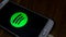 The close up view of the Spotify logo display on an Android phone with wooden table background