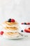 A close up view of a stack of toasted meringues in a stack with berries on top.