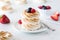 A close up view of a stack of toasted meringues topped with berries ready for eating.