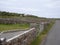 Close up view of stone walls and fence gates along a rural paved road in western Ireland