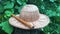 Close up view of straw hat and wooden flute in green garden. Music instrument lying on wooden log