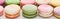 Close up view of sweet colorful French macaroons of different flavors on white background, panoramic shot.