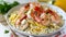 A close-up view of tagliatelle pasta coated in a rich, creamy sauce with succulent shrimp garnished with parsley, on a