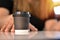 Close-up view, Take away paper coffee black cup on wooden table.