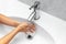 Close-up view of teenage girl washing her hands under water tap in white sink. Prevention of coronavirus. Hygiene against covid-19