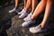 Close up view of three pairs of legs in white sneakers in nature at sunset