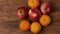 Close up view of three wet red apples and orange mandarins rotating on wooden background.