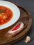 Close up view to Red ukrainian borscht in white plate on wooden plate with bacon and garlic