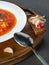 Close up view to Red ukrainian borscht in white plate on wooden plate with dark bread and bacon