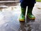 Close up view of toddler legs in colorful green and yellow wellies