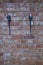 Close up view of two black iron candle holders on brick wall background.