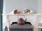 Close up view at two bouquets of blooming tulips, they lie on a white mantelpiece, brown kettle on a wood stove in the foreground