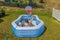 Close up view of two boys in inflatable outdoor swimming pool playing water basketball on backyard on sunny summer day.