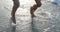 Close-up view of two pairs of female bare feet are running along the coast.