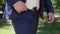 Close-up view of the unknown confident groom in blue suit putting hand in pocket while walking along the park.