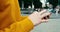 Close-up view of the unknown male hands in yellow sweater texting and browsing on the mobile phone outdoor. 4k footage.