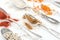 Close up view of various colorful spices in silver retro spoons on white background.