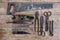 Close up view vintage rusted tools on old wooden table: pliers, pipe wrench, screwdriver, hammer, metal shears, saws and other